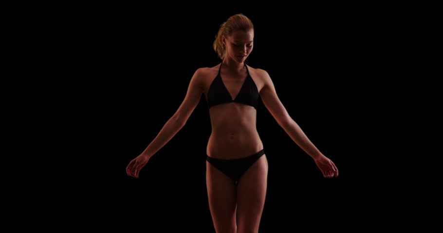 Happy woman spinning in circles on black background with copy space in swimsuit. Millennial woman in swimsuit on studio backdrop with copyspace. 4k