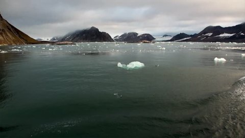Glacier on the coast in the background of water of Arctic Ocean in Svalbard. Wildlife in Nordic badlands. Unique footage on background natural landscape and snow of Spitsbergen.