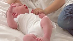 Happy little brother with newborn baby lying in a bed together, kissing and hugging. Siblings. New born baby and three years old brother together. Love. Family. 4K UHD video 3840X2160 Slow motion