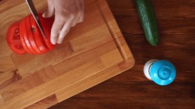 Girl slicing red ripe tomato on wooden board, top view hd video