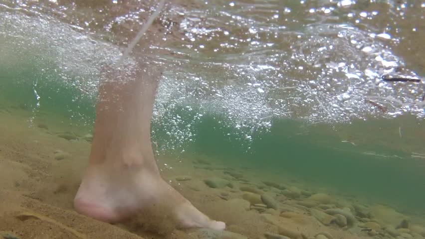 Underwater shot of feet walking on the bottom of the ocean