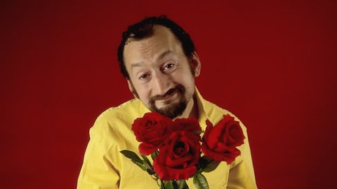 A funny ugly man offers a handful of red roses to the viewer. Valentine's day, dating, anniversary, unexpected, unwanted.
