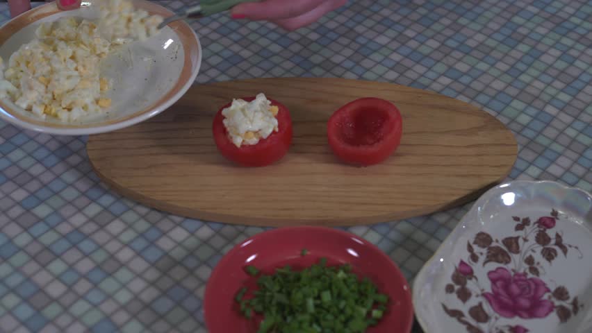 Close-Up of Hands of a Young Girl With Painted Nails Using a Spoon to Stuff the Tomatoes With the Dressing With Finely Chopped Boiled Eggs Mixed With Black Pepper and Mayonnaise