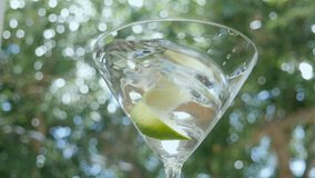 A gin gimlet with a lime swirls in a martini glass in slow motion. The classic mixed drink is an alcoholic beverage representing classic elegance and fun dinner parties. - Powered by Shutterstock - Get 15% off with code: PIKWIZARD15