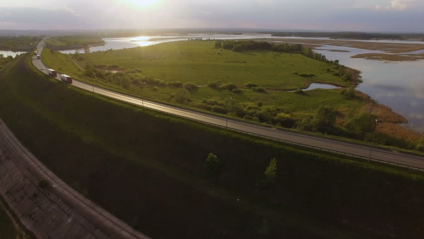 beautiful landscape with a ride on the highway the trucks and a few cars at sunset. aerial view