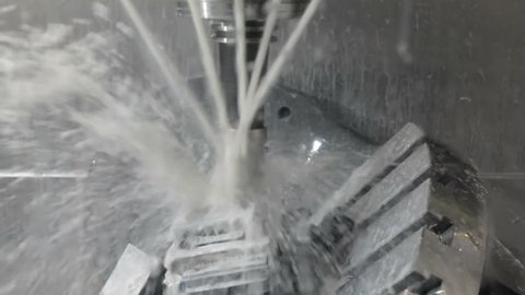 The process of milling a metal part on a CNC machine. The workpiece is machined when a lubricating-cooling liquid is supplied.