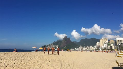 RIO DE JANEIRO - JANUARY 30, 2017: Four young Brazilian lifeguards train in slow motion together in the morning sun against a backdrop of Two Brothers Mountain on the shore of Ipanema Beach.