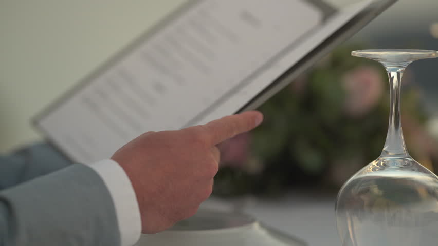 4k video closeup man holding restaurants menu during romantic dinner in santorin