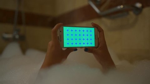 4k uhd Young sexy Girl use mobile phone horizontal in foam bath in hotel room number. Shower white device with green screen and blue cross for tracking close up. Arkistovideo