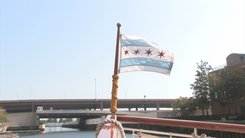 An Illinois flag waving on the nose of a boat in front of a ship on the Chicago