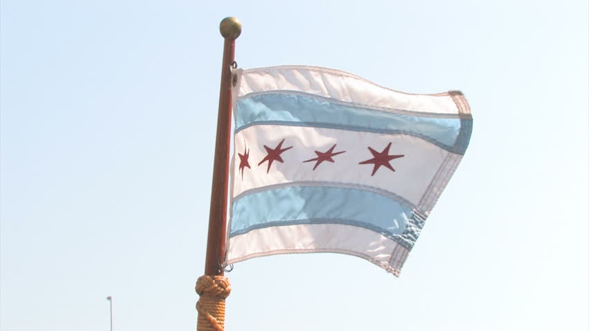 An Illinois flag waving on the nose of a boat in front of a ship on the Chicago