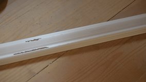 Closeup of applying white glue to a white polyurethane ceiling molding indoors on background of wooden boards