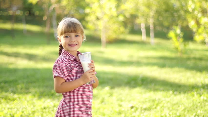 Girl drinking milk outdoors. Thumbs up. Ok.
