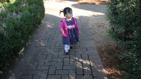 Beautiful Baby Toddler Girl in Pink Outfit walks on path 