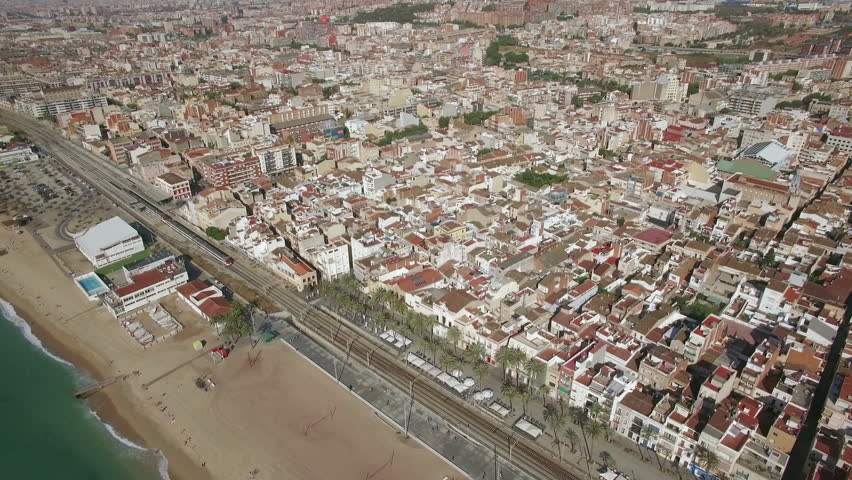 Aerial view of Barcelona coastline and sea, Spain. Beach separated from the city with railway, train moving there