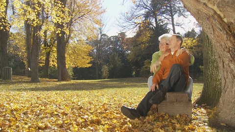 senior couple enjoying sunny day on park bench in autumn part II of II