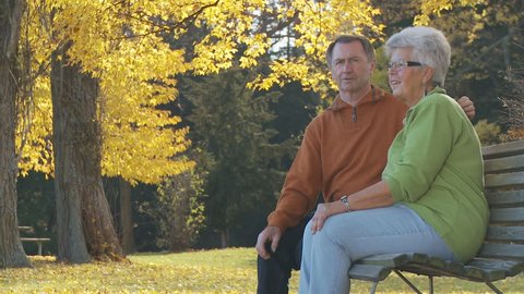 senior couple on park bench in autumn