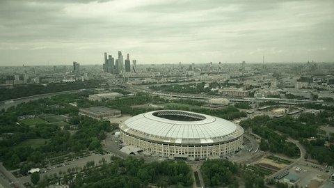 Aerial shot of Moscow cityscape involving famous Luzhniki football stadium and distant business center skyscrapes. 4K video