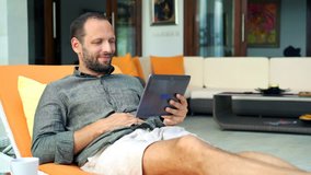 Happy man watching movie on smartphone lying on sunbed at home, 4K
