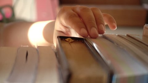Slow motion of woman hand keeping a book into bookshelf in the library.