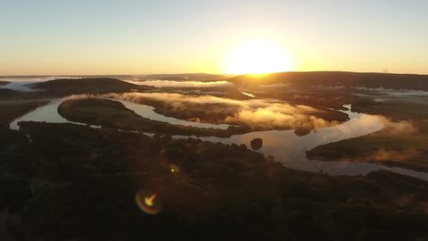 River valley heart bent early morning fog clouds Primorye, Vladivostok. Flight to yellow orange sunrise horizon. Wide open space Aerial drone drift beautiful Russian nature landscape.