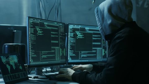 Dangerous Hooded Hacker Breaks into Government Data Servers and Infects Their System with a Virus. His Hideout Place has Dark Atmosphere, Multiple Displays, Cables Everywhere. Shot on RED Camera 4K.