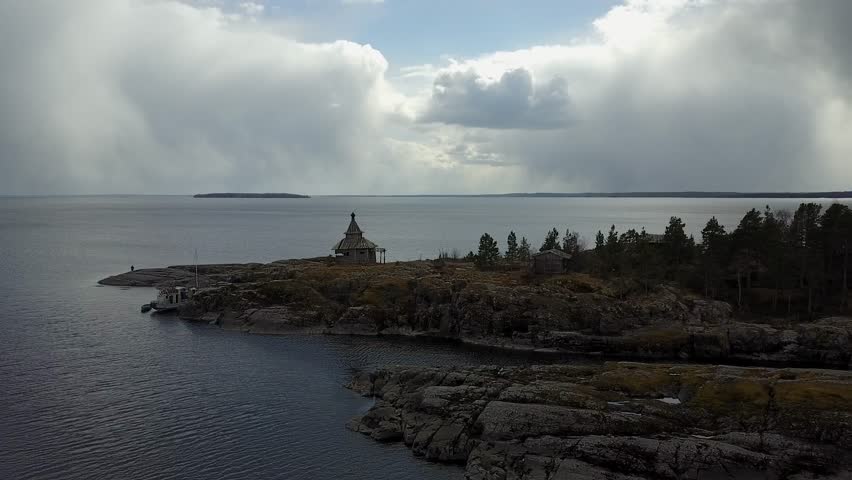 Aerial cinematic view: Abandoned wooden orthodox church on small rocky island in Ladoga Lake, Karelia, Russia