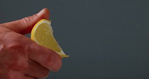 Hand of Man Squeezing Lemon, citrus limonum against Black Background, Slow Motion 4K