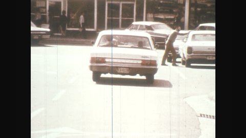 1970s: car drives into strip mall parking lot. Cars park near roses store. car drives main street in small town.