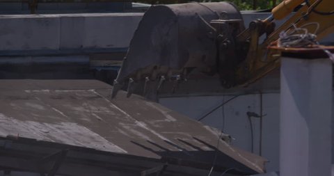 Digger bucket breaks through iron roof during demolition