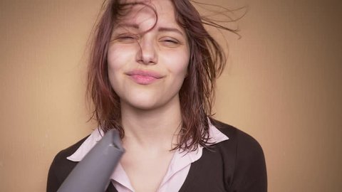 Emotional happy teenager girl make funny faces while drying her hair. Slow motion