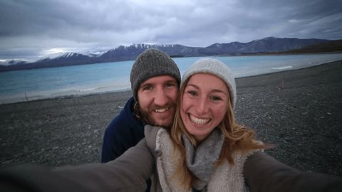 Young couple traveling take selfie portrait by the lake shore, New Zealand
Young couple by the lakeshore take a selfie portrait with the spectacular landscape on the background.