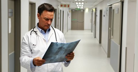 Male doctor examining x-ray in corridor at hospital