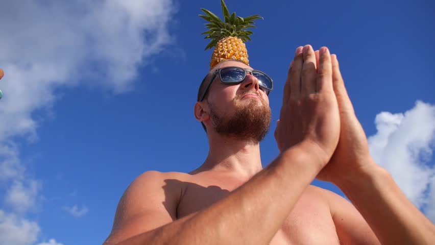 Young Man With Pineapple On Head On Beach Greeting The Sun. Slow Motion. Closeup. HD, 1920x1080.