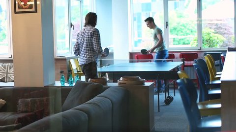 Business people doing a competition and playing a ping pong match in modern startup office