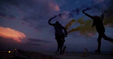 Group of teen friends partying with smoke grenades in the city after sunset