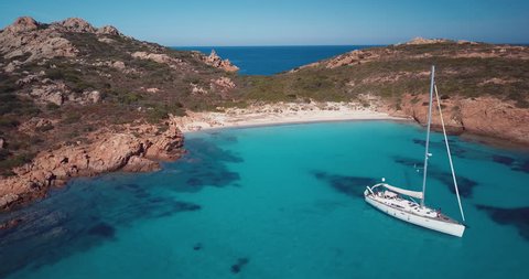 Video from above. Aerial view of a boat in front of the Mortorio island in Sardinia. Amazing beach with a turquoise and transparent sea. Emerald Coast, Sardinia, Italy.