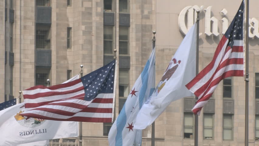 American and Illinois flags waving in front of the facade of a building in