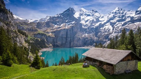 Amazing tourquise Oeschinnensee with waterfalls, wooden chalet and Swiss Alps, Berner Oberland, Switzerland. 
