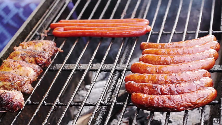 Man grilling sausages and chicken breasts outdoor during holiday festival