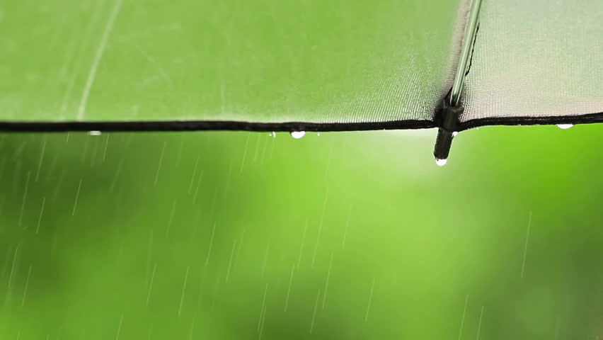 Closeup of rain drops falling of the edge of silver umbrella in the nature with
