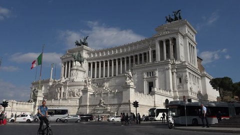 ROME, ITALY - MAY 18, 2017: Bike passes, Italian flag flying, Victor Emmanuel, or Monumento Nazionale a Vittorio Emanuele II at Piazza Venezia, a highly visible tourist destination in Rome.