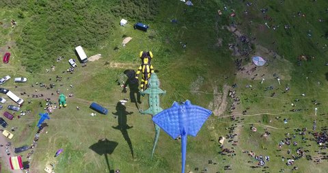 Aerial view of kites with shadow and Tourists on green meadow at Kite Festival