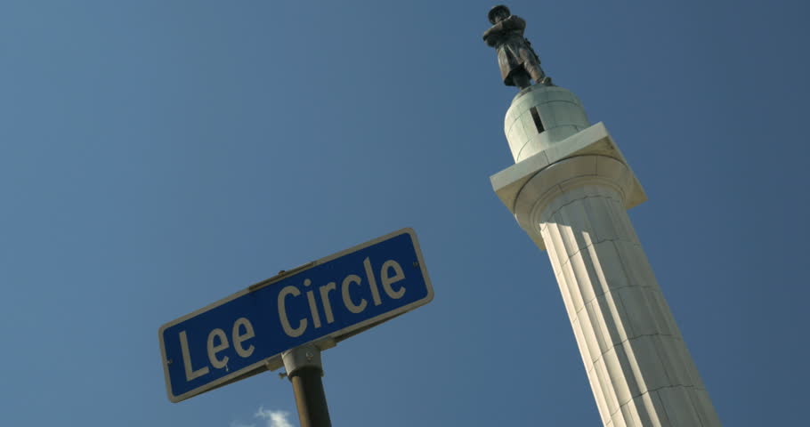 Dutch angle Lee circle Street sign with General Robert E Lee Confederate statue in background with blue sky. The statue was removed by the city on May 19th 2017 4K