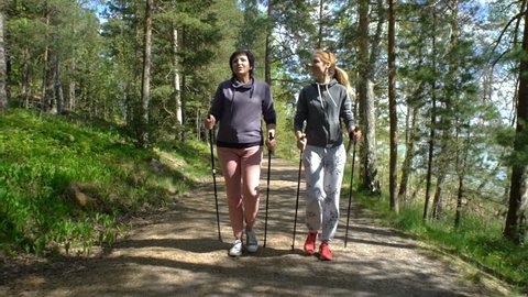 Nordic walking outdoor activity for all ages. Two active women working out in Park. Tracking shot. Slow Motion.