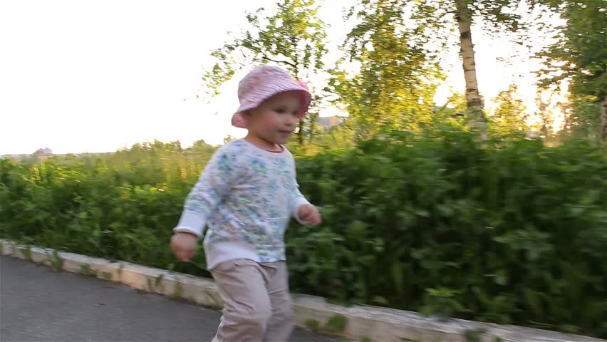 Baby girl smiling running down the alley in the Park.