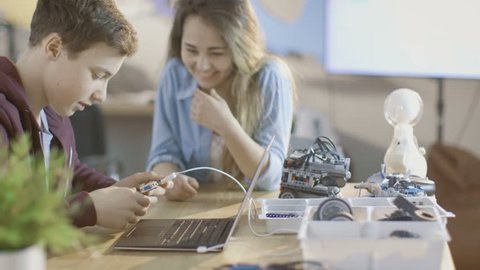 Girl and Boy Program Electronic Device with Laptop For Their Science/ Robotic/ Engineering Class at School. Shot on RED EPIC-W 8K Helium Cinema Camera. Arkistovideo