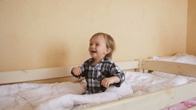 Slow motion video of happy adorable toddler boy jumping on bed