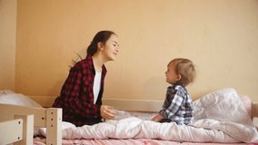 Slow motion video of happy toddler boy and teenage girl dancing and jumping on bed