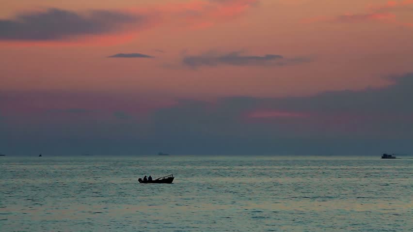 Calm sea with a rowing boat at sunset. 